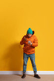 Disappointed. Young caucasian man using smartphone, serfing, chatting, betting. Full length portrait isolated on yellow background. Concept of modern technologies, millennials, social media.