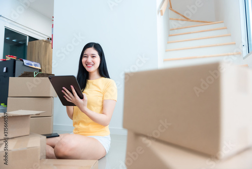A happy girl uses a tablet to take orders that the customer ordered in the goods room.