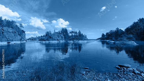 The chic view of the rocky islands on the lake is toned in a trendy classic blue color. The Island Honkasalo
