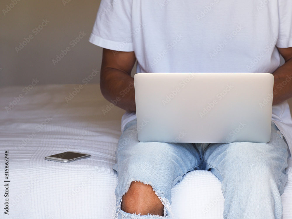 Man in casual dress, work on the laptop sitting in the bed at home. Man in casual dress, work on the laptop sitting in the bed at home.