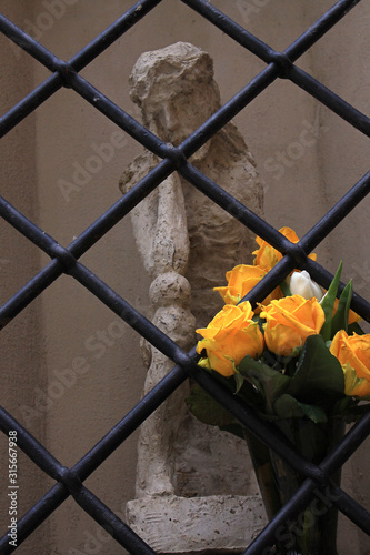 Bouquet of yellow roses at the statue of Jesus behind the black bars photo