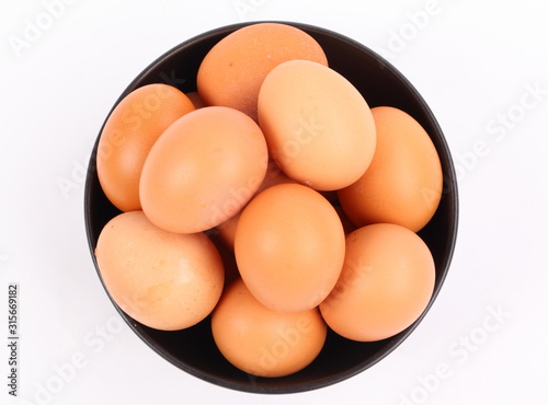 brown eggs in black bowl on white background 