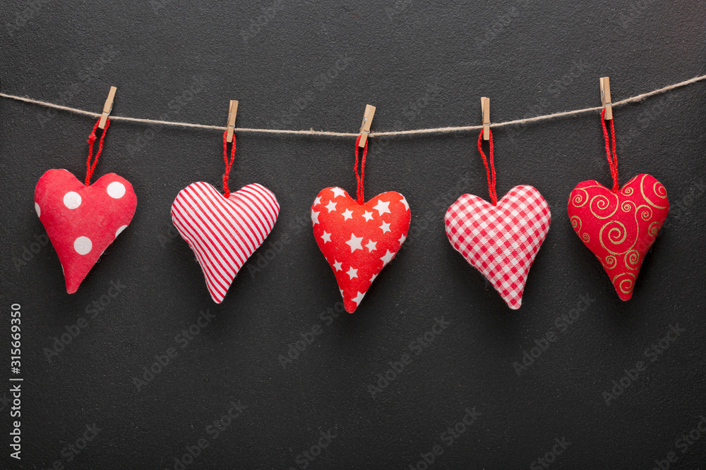 Fototapeta premium February 14 is Valentine's Day. Symbolism of the day of lovers hearts. Homemade hearts on a rope on a dark background