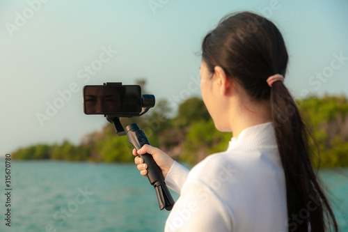 Blogger Asian woman record vlog video and sharing content on streaming platform with Social Network. female enjoy in front of camera using mobile phone make vlogging live feeds on social media network photo