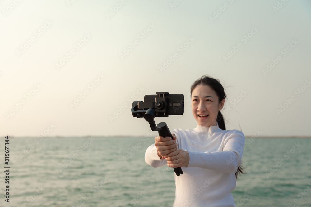 Blogger Asian woman record vlog video and sharing content on streaming platform with Social Network. female enjoy in front of camera using mobile phone make vlogging live feeds on social media network Blogger Asian woman record vlog video and sharing content on streaming platform with Social Network. female enjoy in front of camera using mobile phone make vlogging live feeds on social media network