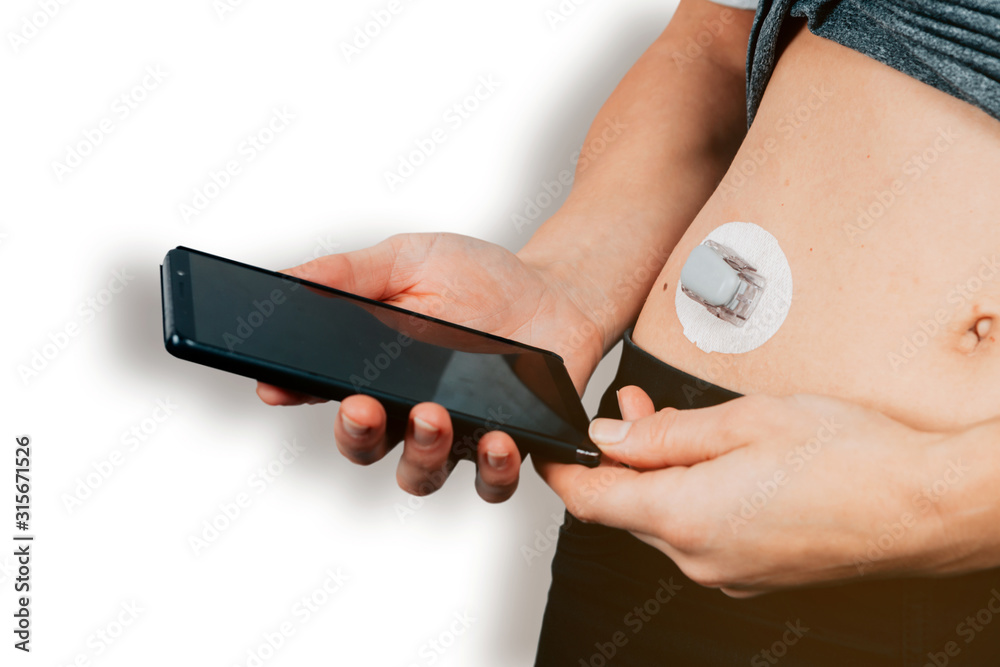 Φωτογραφία close up of female hands holding a mobile phone nearby a diabetes sensor - gluco