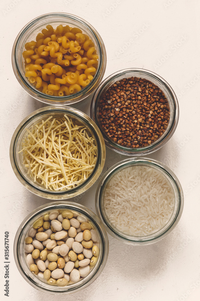 Various raw cereals, grains, beans and pasta for cooking healthy food in glass jars on a wooden table, light background flat, Clean food, vegan, balanced diet,zero waste,eco friendly,plastic free Various raw cereals, grains, beans and pasta for cooking healthy food in glass jars on a wooden table, light background flat, Clean food, vegan, balanced diet,zero waste,eco friendly,plastic free
