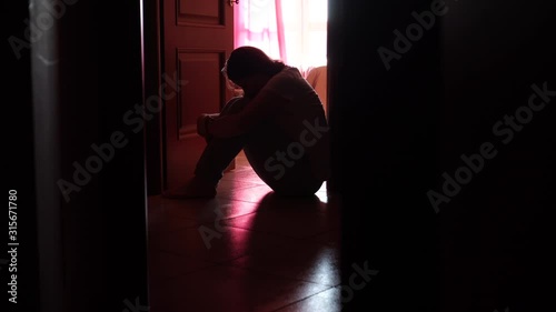 Silhouette of a young girl sitting on the floor in the dark room, depression, pain. Domestic violence, family problems, Stress, violence, The concept of depression and suicide.