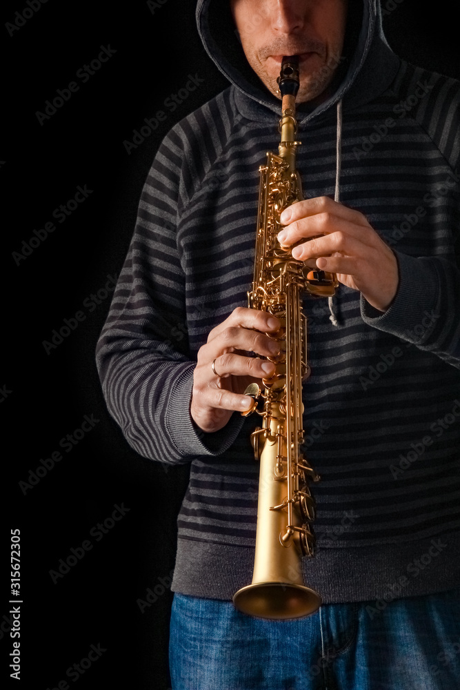 Fototapeta premium soprano saxophone in the hands of a guy on a black background