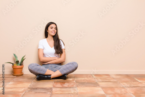 Quadro em tela young pretty woman smiling to camera with crossed arms and a happy, confident, s