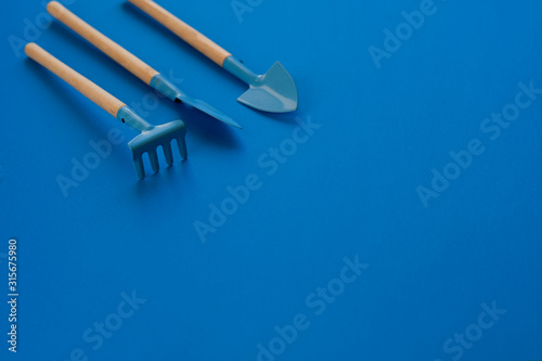 resource of gardening tools shovels and rake on blue classic background
