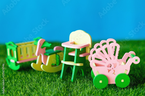 Childhood in furniture. Conceptual photography Children's furniture, crib, high chair stroller on the green grass