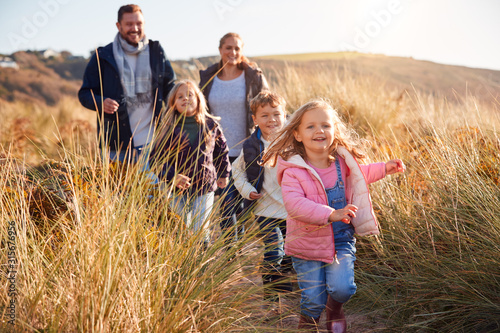 Fotografia Family Walking Along Path Through Sand Dunes Together