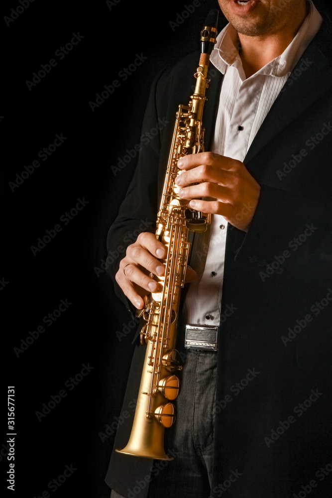 Fototapeta premium soprano saxophone in the hands of a guy on a black background