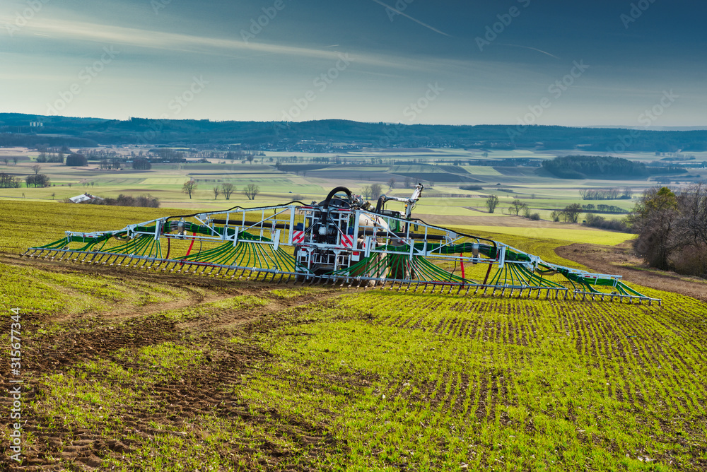 Fototapeta premium Traktor mit Schleppschlauch Güllefass auf dem Feld