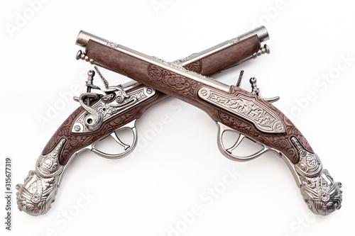 Obraz na płótnie Firearms dating to the american revolution and antique collectables concept with ornate old fashioned dueling flintlock pistols crossed in duel isolated on white background with clipping path cutout w salonie