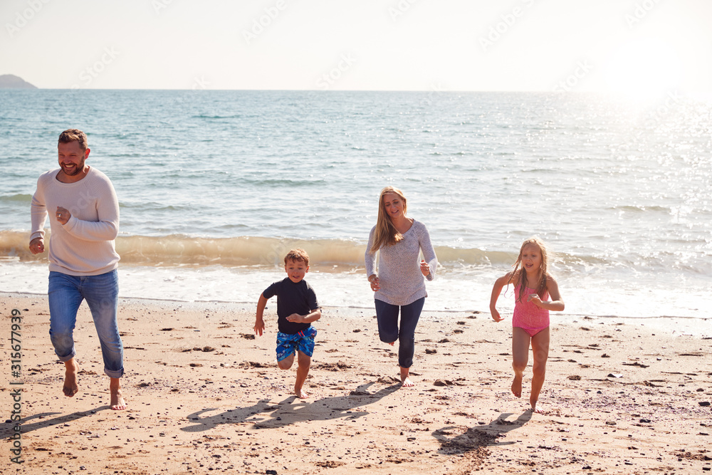 Family On Beach Running Across Sand Away From Sea Family On Beach Running Across Sand Away From Sea