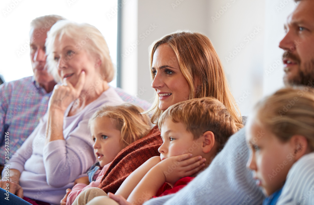 Multi-Generation Family Relaxing At Home Sitting On Sofa Watching Television Together Multi-Generation Family Relaxing At Home Sitting On Sofa Watching Television Together
