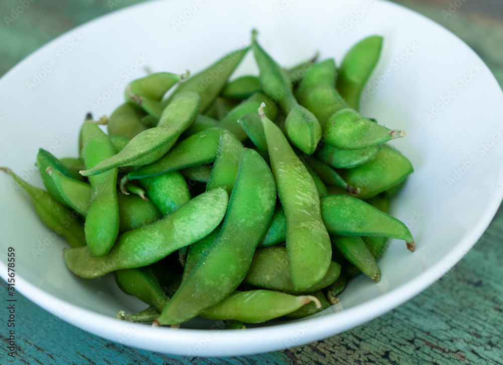 Close shot of steamed fresh edamame bowl on wooden background Close shot of steamed fresh edamame bowl on wooden background