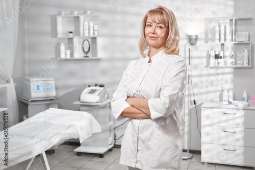 Portrait of successful professional doctor cosmetologist dermatologist woman in her beauty salon smiling in white medical clothes close-up photo