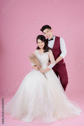 Happy young bride and groom on the pink background. Wedding couple  new family  wedding dress. Bridal wedding. Love concept