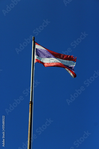 Thailand flag is waving with high pole with blue sky background. photo