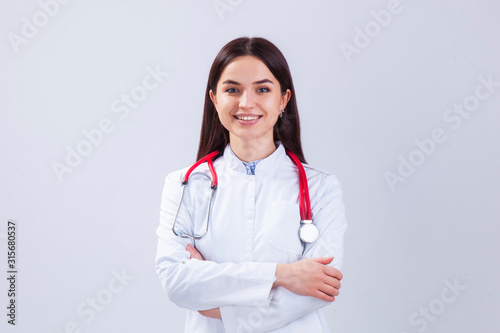 Medical concept of beautiful female doctor in white coat with phonendoscope. Medical student general practitioner. Woman hospital worker looking at camera and smiling  studio  gray background