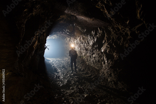 Underground gold mine shaft tunnel drift with miner and light
