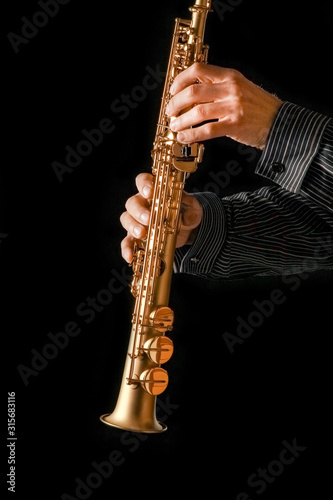 soprano saxophone in hands on a black background