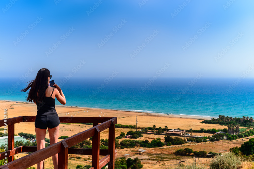 beautiful woman photographs the landscape standing on the mountain