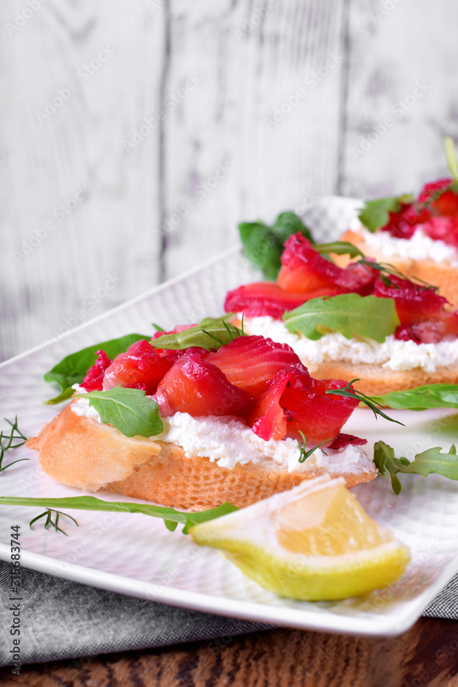 Trout Gravlax on the slice of white bread with ricotta topped with greenery against the white background. Nordic cuisine meal