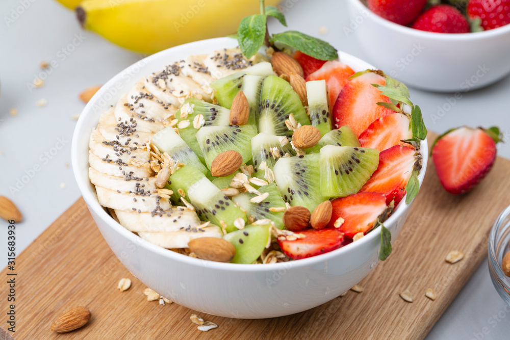 Healthy breakfast bowl: smoothie with banana, strawberries, kiwi, granola, almonds and Chia seeds. 