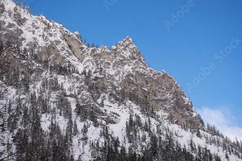 Detail of mountain face with rocks, snow and trees near Green lake (Gruner see) in sunny winter day. Famous tourist destination for walking and trekking in Styria region, Austria