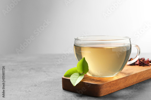Cup of green tea and leaves on grey table. Space for text