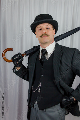 Foto Portrait of Businessman in Dark Suit and Bowler Hat and Leather Gloves Holding Umbrella