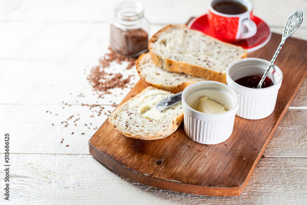 Sliced toast bread with butter on wooden cutting board. Morning breakfast with coffee, butter and toasts.