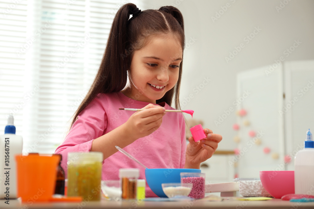 Cute little girl making homemade slime toy at table indoors Cute little girl making homemade slime toy at table indoors