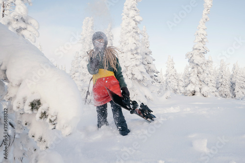 snowboarder female in snowy Christmas trees winter forest have fun and tossing snow