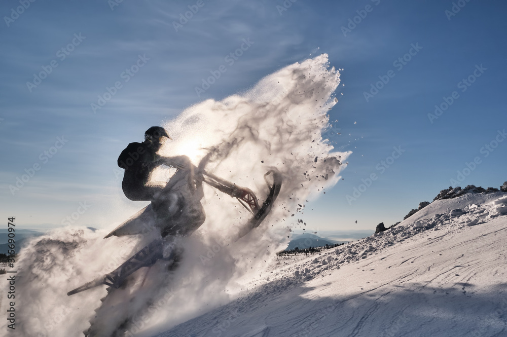 Snowbike rider in mountain valley. Modify dirt bike with snow splashes and trail. Snowmobile sport riding