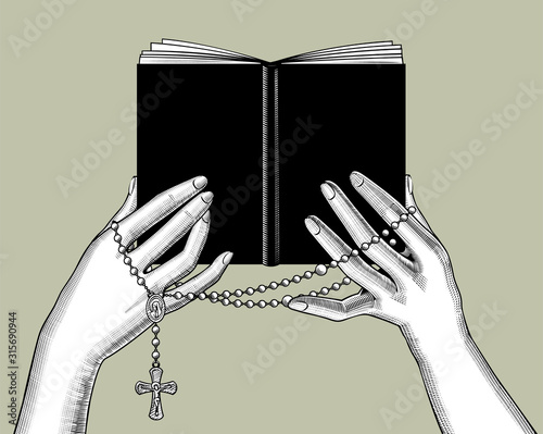 Hands holding a black book and prayer beads