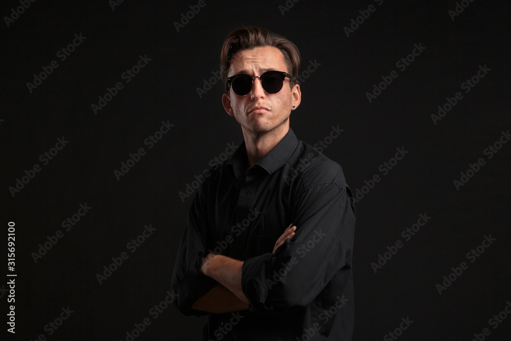 Fototapeta premium Confident stylish man in black eyeglasses isolated over black background.