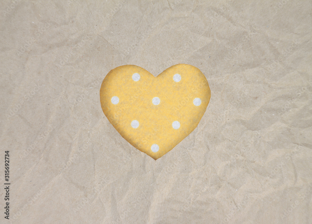 Obraz premium Felt heart with polka dot pattern on craft paper. Crumpled paper texture. Valentine's day stock photo for web, print and wallpaper. With empty space for text.