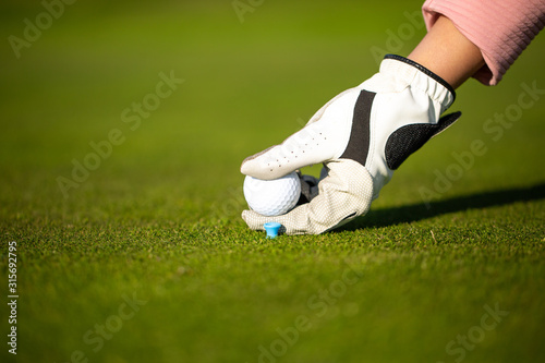 Professional golf player setting up the golf ball on a stand on grass during golf match