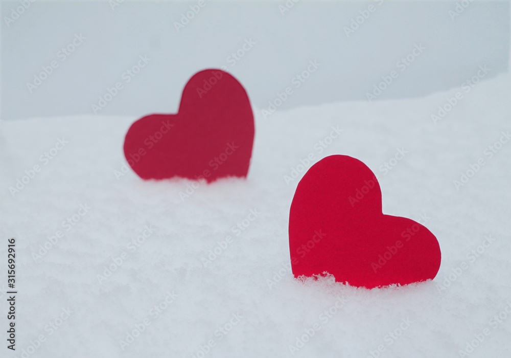 Fototapeta premium Two red felt hearts on the snow. Handmade for the celebration and holiday. Stock Photography for Valentine's Day with empty space for your text. For web, print, cards, invitations and wallpapers.
