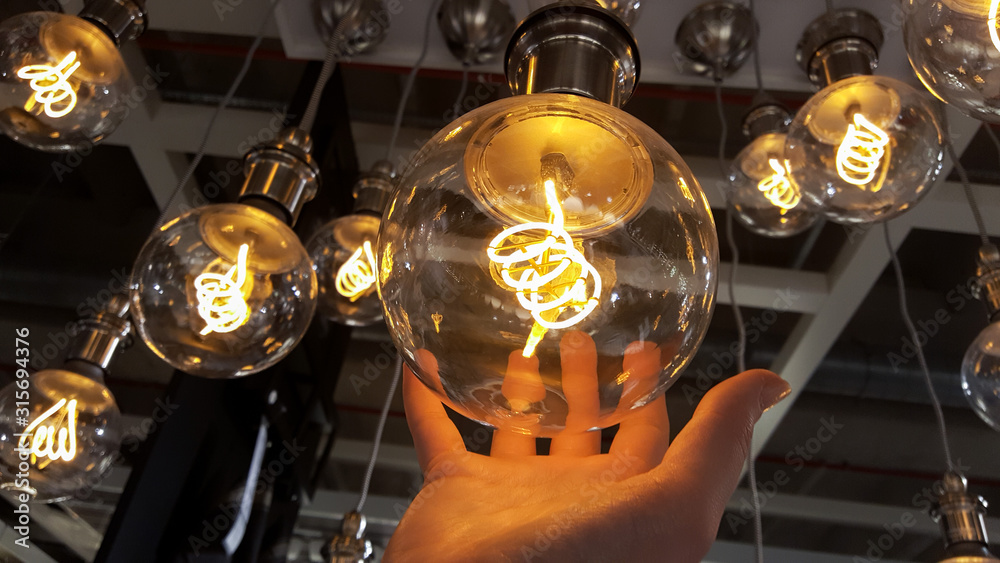 Round filament led bulbs, hand holding light bulb, background - obrazy, fototapety, plakaty 