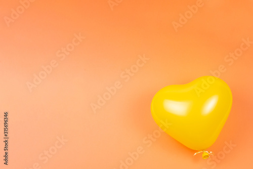 Yellow heart ballon on orange background.