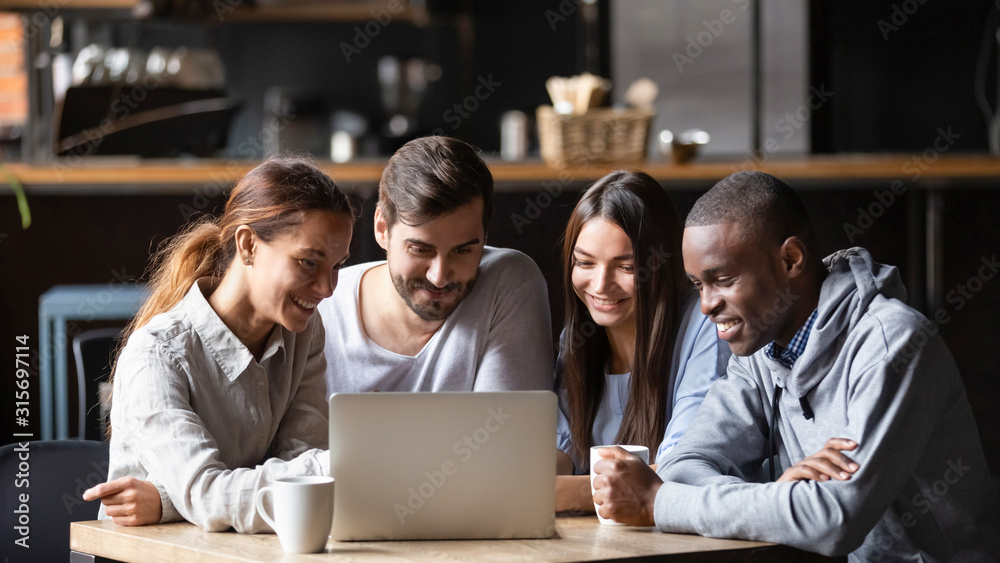 Diverse friends hang out in cafe using laptop