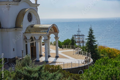  Church of St. Nicholas Mira patron saint of travelers and sailors on seashore. Observation deck around temple against blue surface of Black Sea. Malorechenskoye, Crimea, Russia, October, 2019. photo