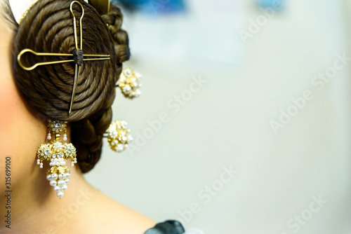 Typical Valencian fallera bun, traditional Spanish hairstyle and decorative earrings, negative space for text photo