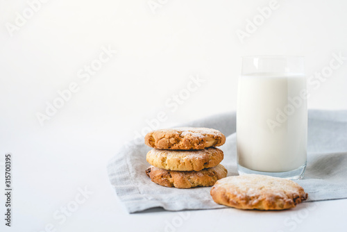 Stacked cookies on a linen napkin and a glass of milk. Close up. Top view.